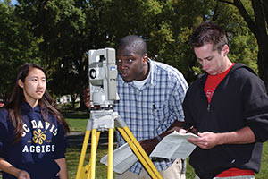 three students using surveying equipment on the Mrak Mall