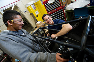 Two male students working on a racecar in the engineering department